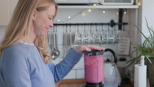 Woman, smoothie and blender in kitchen with detox, fruits and nutrition drink at home. Breakfast, weight loss and female person smile with cooking and nutritionist food in the morning in a house
