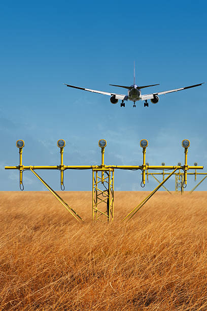 Airplane ready to land flying over yellow landing lights stock photo