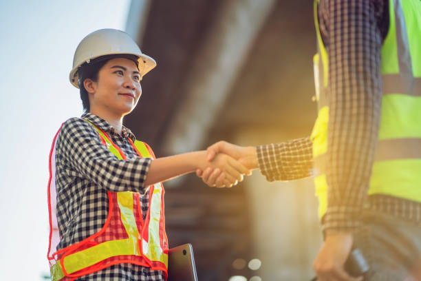 istock Asian Female Engineer and Architect Standing on Construction Site Holding Hands in Successful Business Cooperation 1532163214