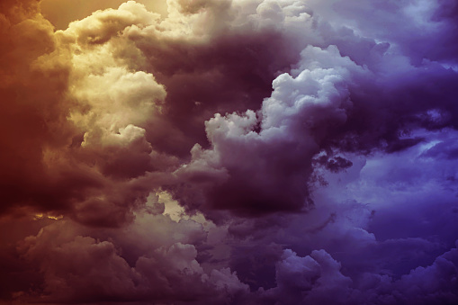 Yellow orange red purple violet blue clouds. Storm hurricane thunderstorm rain wind. Dark colorful dramatic sky. Flash glow light lightning. Background for design.