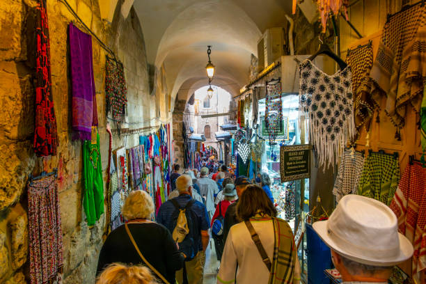 a crowded narrow tunnel passageway through the historic marketplace and bazaar in the old city of jerusalem, israel. - covered bazaar imagens e fotografias de stock