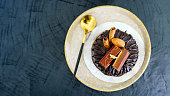 Close-up of round brown chocolate cake on blacked on black wooden background.