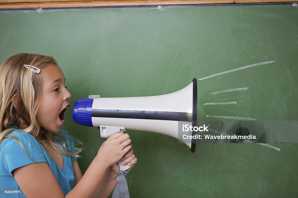 Joven con un megáfono niña en edad escolar pateando - Foto de stock de Agarrar libre de derechos