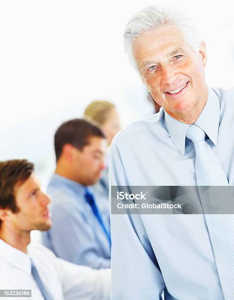 Uomo Daffari Sorridenti Con I Suoi Colleghi In Background - Fotografie stock e altre immagini di Abbigliamento elegante