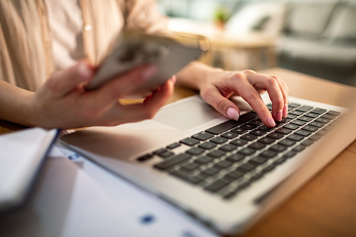 Close up of a Young woman going over her finances at home while using a banking app on her phone