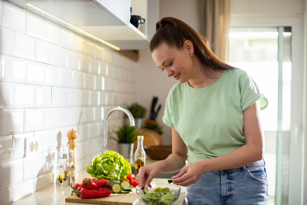 istock Young woman cutting and preparing vegetables in a kitchen at home 1532304280