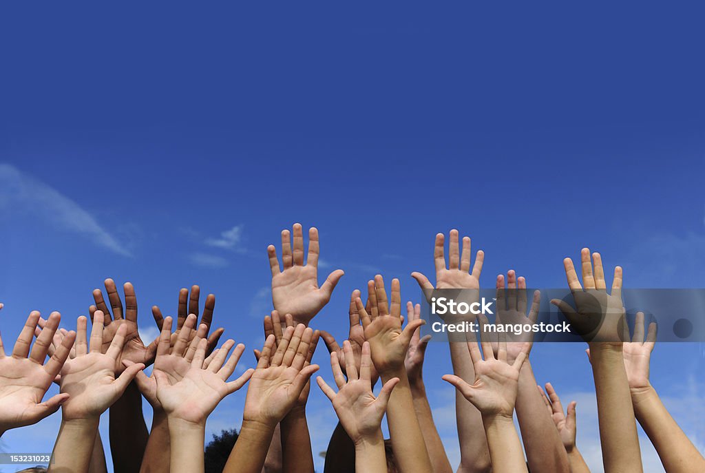 Hands against blue sky Hand Raised Stock Photo