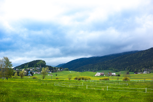 Meaudre, Le Vercors, France: Green pastures, village houses in springtime, and low clouds.