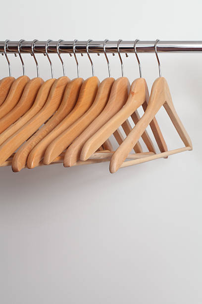 Clothes hangers Photo of empty wooden clothes hangers in a retail store. clothes hanger rod stock pictures, royalty-free photos & images