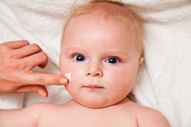 istock Creaming face of infant girl after bath 153243774