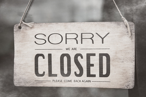 A closed sign posted on glass door of store. Concept of shop service business closed on holidays.