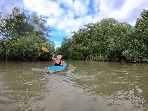 Senior woman exploring tropical rainforest by kayak