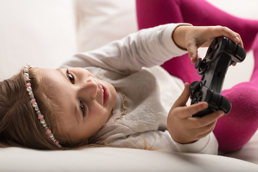 Girl gaming on home sofa, thrilling challenges embraced under parental guidance