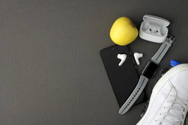 Photo of Objects to exercise on a mat with cell phone, apple, bottle of water, headphones, tennis towel and watch