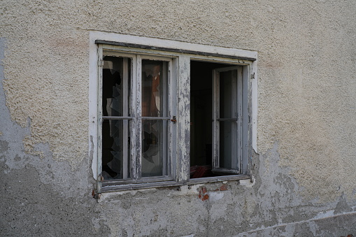 Window with a frame covered with old weathered paint, on a stone wall, framed in red brick. From the windows of the world series.