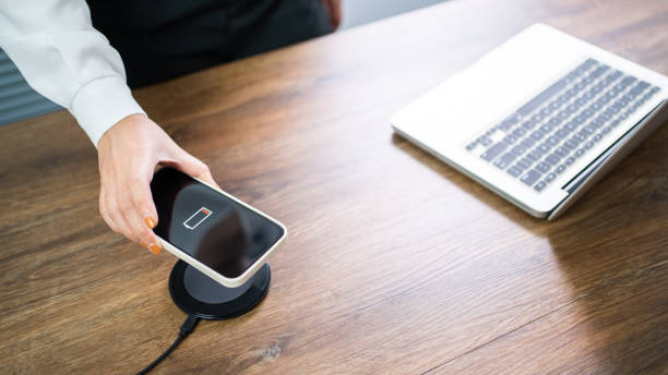 istock Charging mobile phone battery with wireless charging device in the table. Smartphone charging on a charging pad. Mobile phone near wireless charger Modern lifestyle technology concept. 1532505575