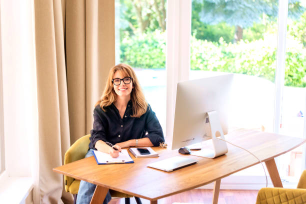 istock Attractive mid aged woman sitting at home and using compter for work 1532543736