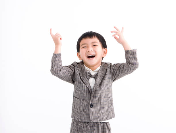 Elementary age boy dressed in vintage clothes is working a film projectionist. The boy is standing before the film projector. He is having fun in a light beam of the projector. Studio shooting, retro style