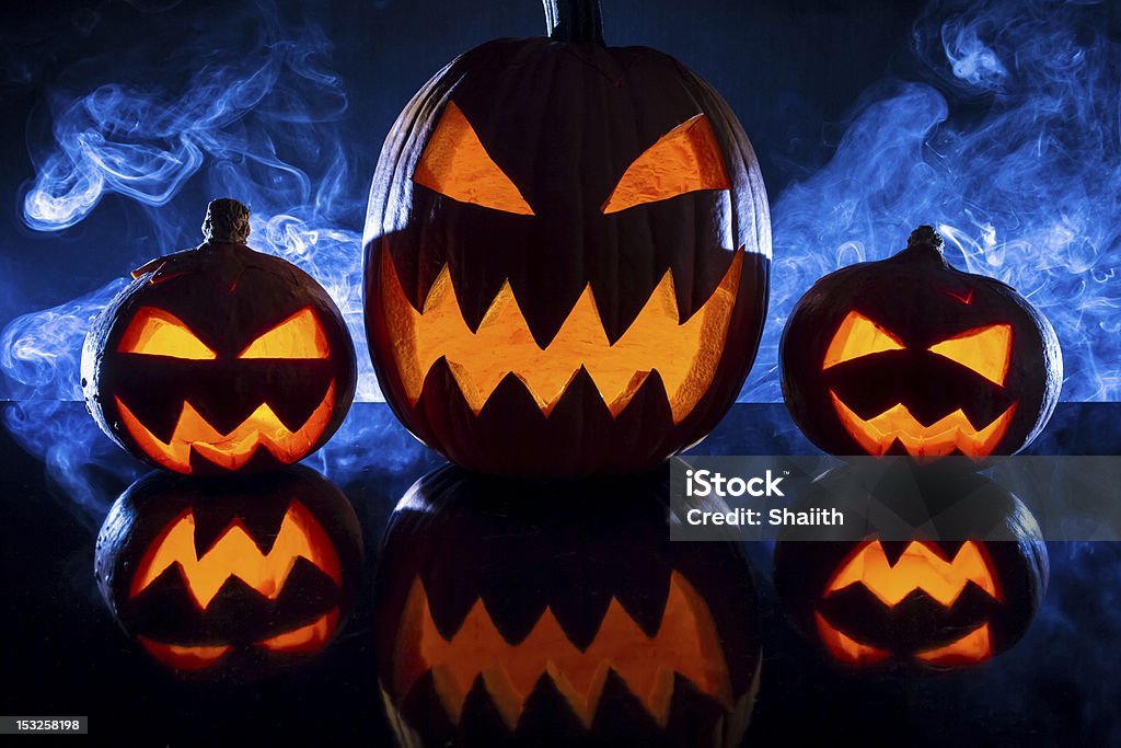 Three halloween pumpkins in the smoke background Three halloween pumpkins in the smoke background. American Culture Stock Photo