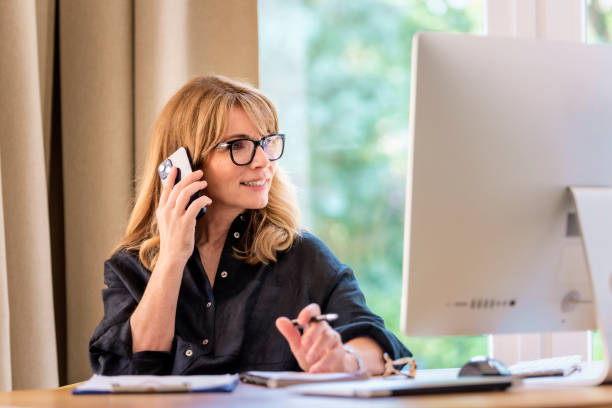 istock Mid aged businesswoman using computer and mobile phone and working from home 1532590298