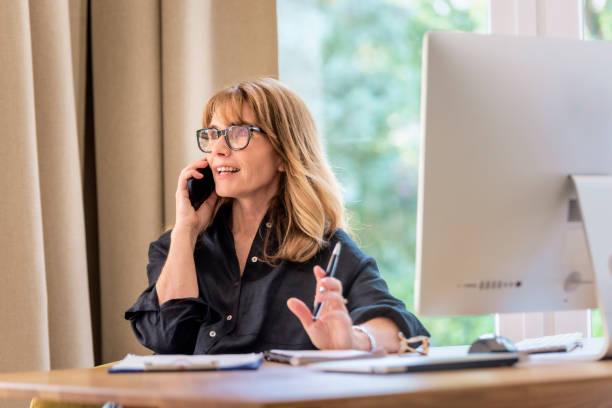 istock Mid aged businesswoman using computer and mobile phone and working from home 1532607454