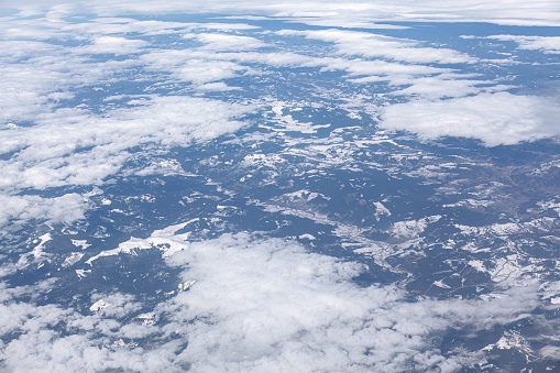 Aerial view of clouds and snowy mountains . View from airplane window