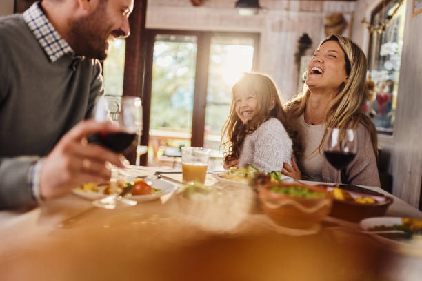 istock Cheerful mother and daughter talking to a father at dining table. 1532621711