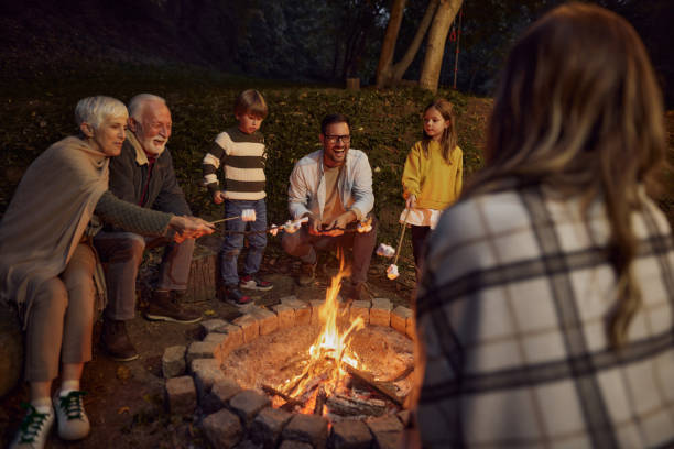 istock Happy multi-generation family roasting marshmallows on fire by night. 1532632420