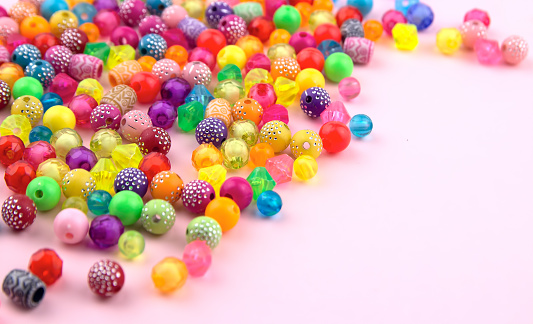 Combination of beads and beads on a pink background. Mock up and abstract, colorful background. concept of needlework, creativity and hobbies.