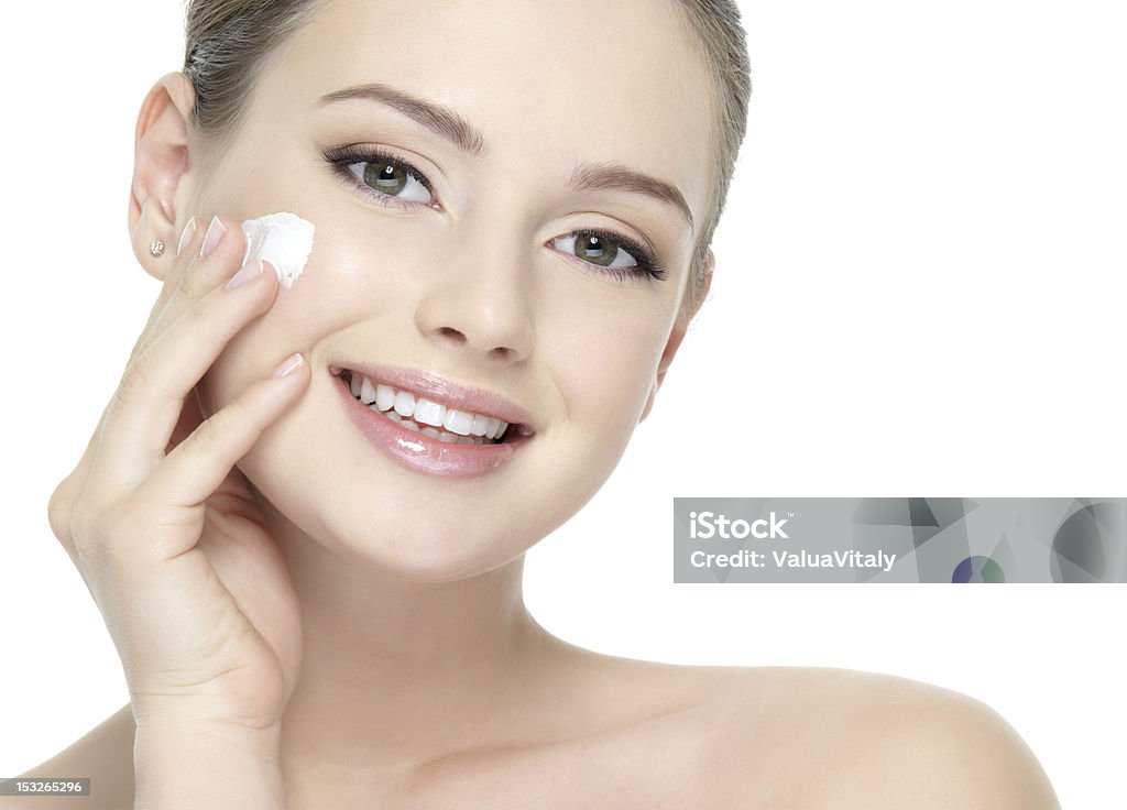 Beautiful smiling woman applying  cream on cheek Beautiful face of young smiling woman applying cream on the cheek - white background Adult Stock Photo