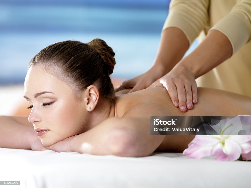 Spa massage for young beautiful woman Young beautiful girl in beauty salon getting spa massage - colored background Adult Stock Photo