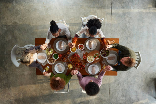 istock Above view of young friends praying before lunch at dining table. 1532659098