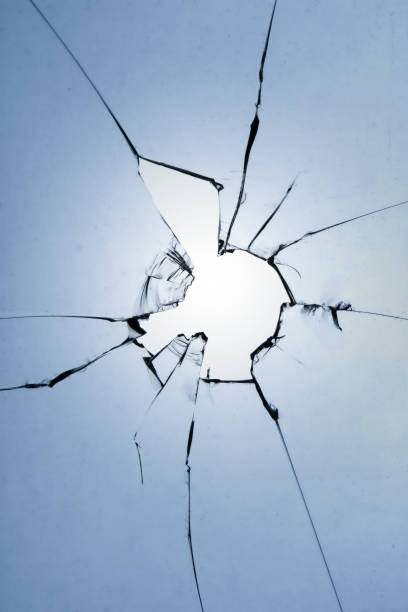 istock A hole with cracks on the glass. Broken window on a blue background. 1532712095