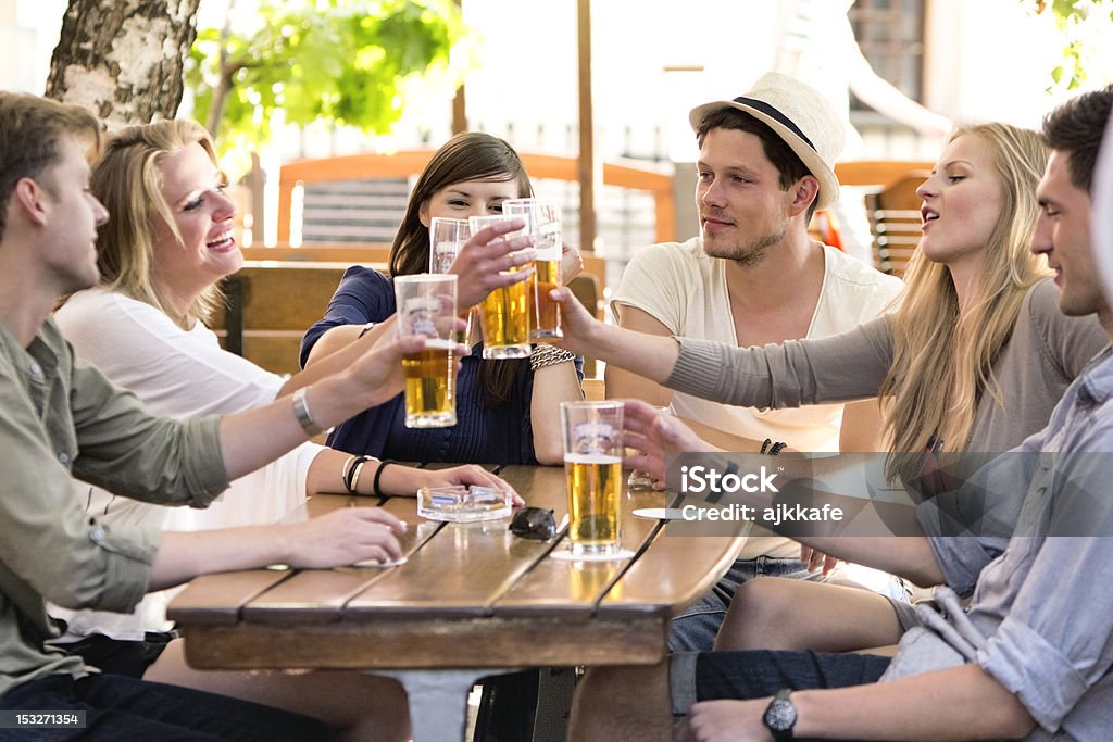 Friends drinking beer Group of  happy young people raising toast with beer in outdoor pub Beer Festival Stock Photo