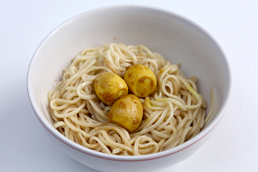 Instant noodles with quail egg topping in bowl isolated on white background with chopstick. Asian and Chinese style fast food concept.