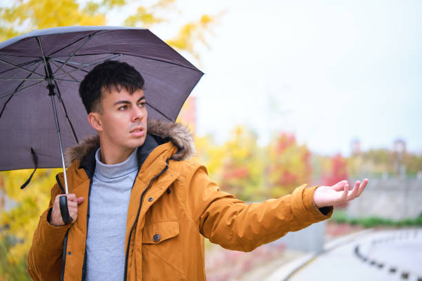 istock Young man holding an umbrella and checking if it is still raining. 1532732508