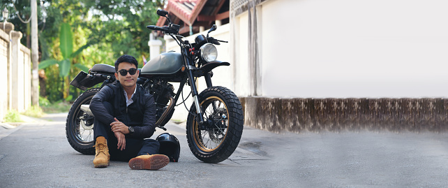 Banner Asian man motorbike in black leather jacket travel rider trip. Panorama Handsome Men wear sunglass outdoor lifestyle freedom rider. Hipster asian man hobby ride motor bike with copy space
