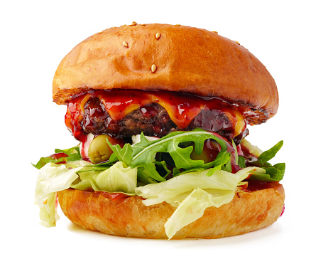 Close up image of a selection of freshly flame grilled burgers in a row on a wooden counter at a London street food market. Each of the burgers has its own label, on which is written the contents of the burger. The burgers are sandwiched between glazed buns, and presented on beds of fresh green lettuce and stuffed with melted cheese and red onion. Horizontal colour image with copy space and beautiful bokeh background.