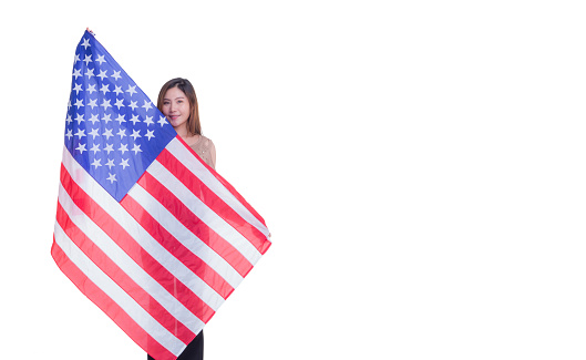 A woman holding the American flag and looking at the camera while standing on a white background. Space for Text. 4th of July. Celebrate American National Day. Labor Day. Independence Day