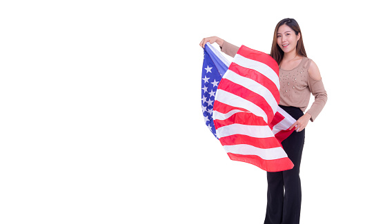 A young woman holding the American flag and looking at the camera while standing on a white background. Space for Text. 4th of July. Celebrate American National Day. Labor Day. Independence Day