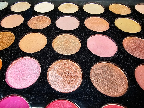 Different colors of eyeshadow in a palette in the cosmetics store.
