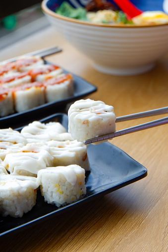 Sushi on the plate is taken using chopsticks and then dipped in sauce