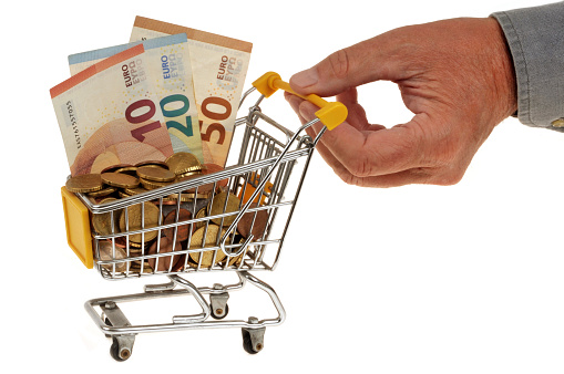 Purchasing power concept with a supermarket trolley full of euros being pushed by a hand close up on a white background