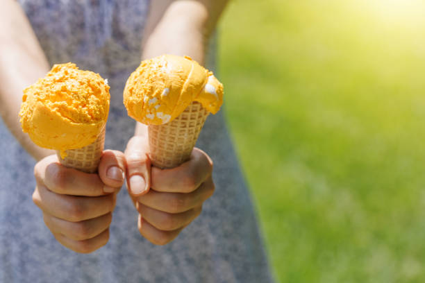 Woman's hands holding refreshing ice cream in waffle cones treats with a hint of zesty lemon flavour. With copy space