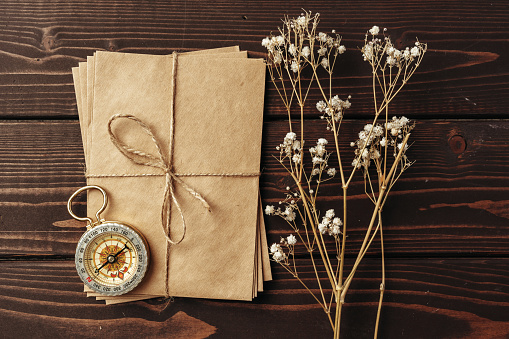 Letter paper, dry flowers, compass on wooden desk top view photo