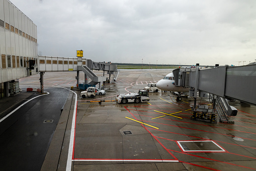 Wide shot of a plane parked up at an airport ready to take passengers on vacation. The weather is rainy.