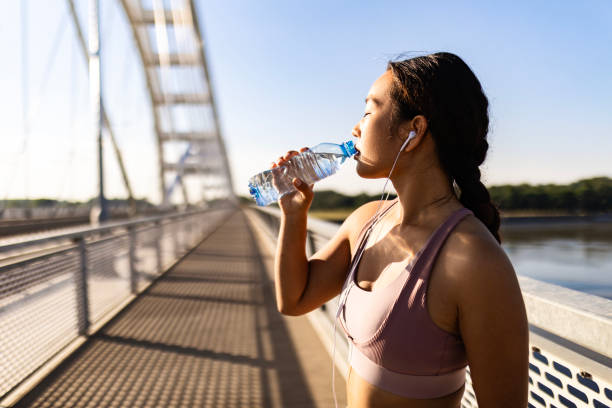 istock Female runner on city bridge taking a break hydrating 1532898032