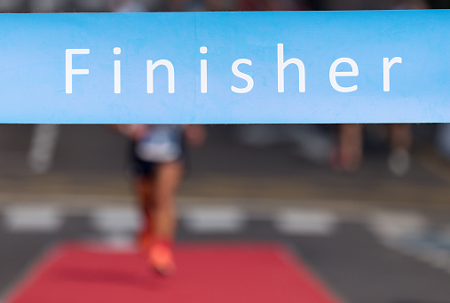 Man running towards the finish line, male runner win the race outdoor in the city. Passes finish line as a winner