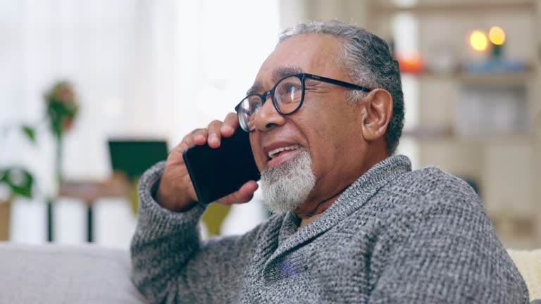 Phone call, relax and senior man on a sofa while sitting in the living room of his modern house. Communication, technology and elderly male in retirement resting while on mobile conversation at home.