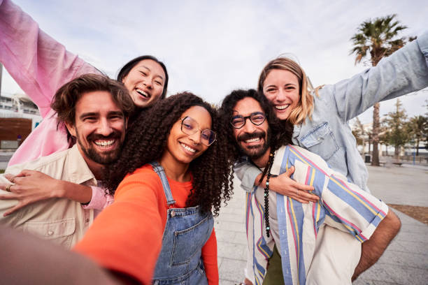 istock Happy group of friends having fun outdoors, doing piggyback while taking a selfie for social media. 1532942073